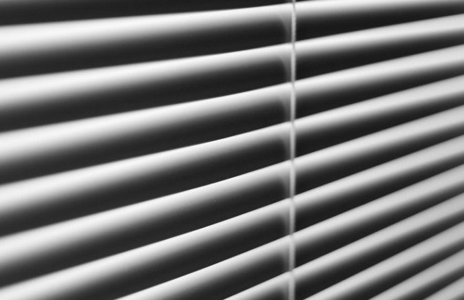 Primer plano en blanco y negro de las lamas de aluminio de una veneciana con su cordón de accionamiento